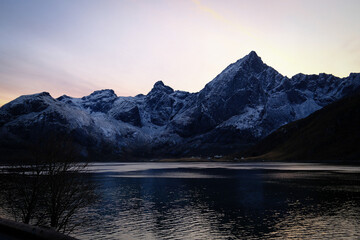 Snow Covered Mountain Peaks Reflected in a Calm Norwegian Fjord at Twilight with Soft Pastel Sky and Cold Nordic Light
