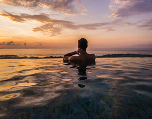 Person in infinity pool at sunset overlooking ocean