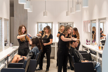 Hairdressers styling client hair in modern salon
