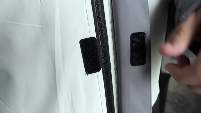 A man fastens the zipper and Velcro on a warm jacket. Down jacket for winter