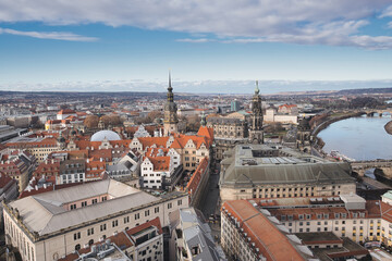 Obraz premium Dresden old town cityscape showcasing historic architecture, including the hofkirche and semperoper, with the elbe river flowing through the urban landscape under a partly cloudy sky