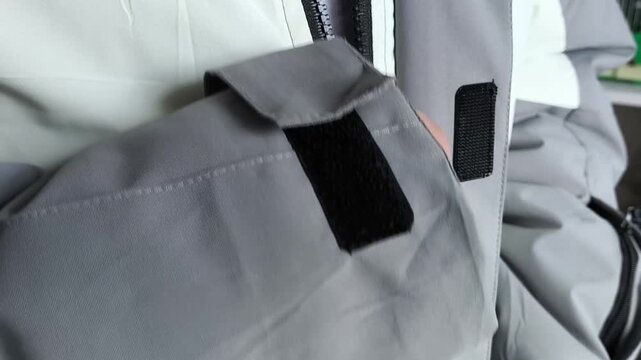 A man zips up a warm winter jacket in close-up. Down jacket for cold weather.