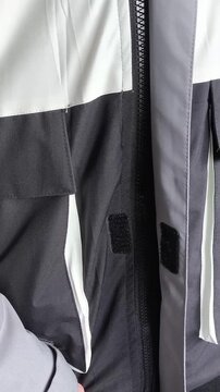 A man fastens and unzips a warm winter jacket in close-up.