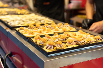 Asian and Chinese traditional cuisine: grilled squid skewers with garlic sauce, sold at street food stalls