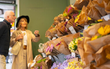 Senior couple choosing bouquets in a flower shop, enjoying market day shopping