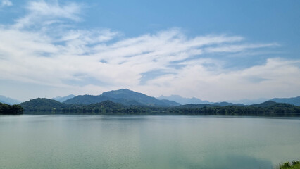 A serene masterpiece captured at Kandalama Lake, where nature's reflection paints a tranquil scene. The still waters mirror lush greenery and a clear blue sky, creating a captivating blend of beauty