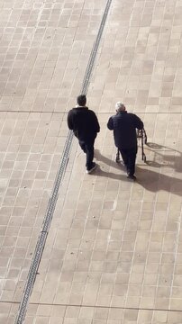 cuidador asistente social y se&ntilde;or anciano con andador caminando juntos por el patio