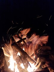 Night campfire in a winter forest. Flames and glowing embers on snow create a contrast of warmth and cold, symbolizing survival, nature connection, and calm during a winter adventure.