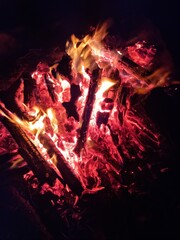 Night campfire in a winter forest. Flames and glowing embers on snow create a contrast of warmth and cold, symbolizing survival, nature connection, and calm during a winter adventure.