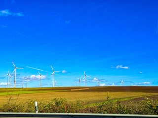 Wind farm with multiple turbines on a hill under a clear blue sky