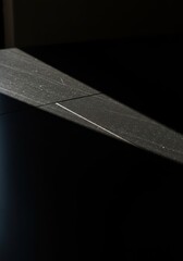 Intense sunlight reflecting sharply on a polished black surface, creating dramatic contrast and deep shadows in the modern setting ,vibrant ,vertical ,backdrop