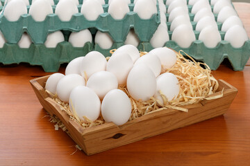 Fresh white eggs in rustic baskets and cardboard boxes.