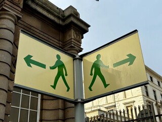 Richtungsweisende Schilder f&uuml;r Fu&szlig;g&auml;nger in gelb mit gr&uuml;nen M&auml;nnchen
