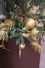 New Year's decorations made of fir branches and golden balls in a brown vase