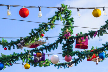 A New Year's garland with illuminations, fir branches and toys against a blue sky