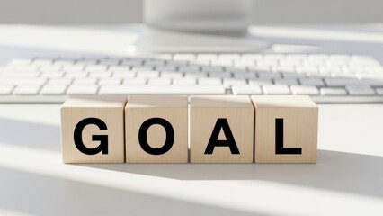 Wooden blocks spell goal on white desk with keyboard background