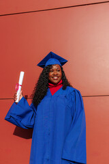 Young black woman smiling, proudly holding diploma after academic achievement