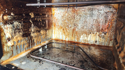 Dirty oven interior covered with grease stains rust and burnt food residue, symbol of household...