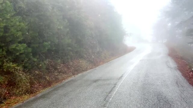 View of a misty mountain road winding through Mount Olympus National Park in Pieria, Greece, leading from Litochoro town to the Prionia area, surrounded by autumn forest and atmospheric fog.