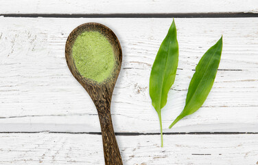 Homemade wild garlic salt made with Allium ursinum leaves, known as ramsons, buckrams, broad-leaved garlic, wood garlic, bear leek or bear's garlic. Plant leaves and herbal salt on wood spoon on white