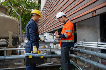 Professional technicians recording field maintenance data at industrial pipe system