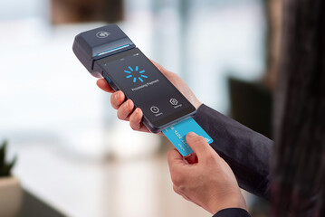 Portable POS terminal showing payment processing screen while card is inserted, illustrating transaction progress, digital checkout flow, and modern retail payment systems