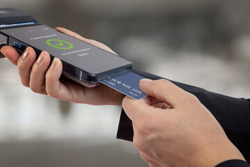 Payment card being processed by portable POS terminal with confirmation screen, representing secure transaction, electronic payments, and financial technology in retail environment