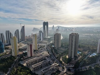 Fototapeta premium misty morning urban landscape featuring clustered skyscrapers and soft sunlight filtering through haze