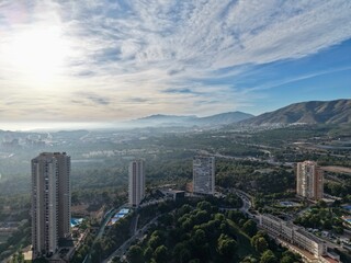 Fototapeta premium bright city scene, sunshine illuminates cityscape alongside mountain range and scattered structures