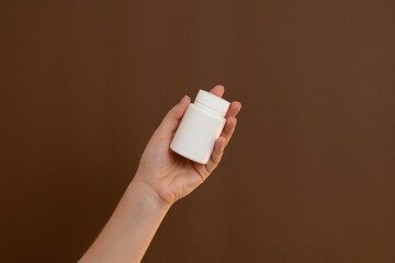 Hand holding blank white medicine supplement bottle