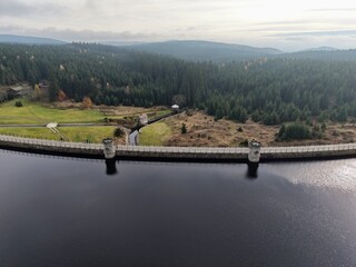 overview of dam, maintenance pathway along dam with controlled water flow and natural scenery