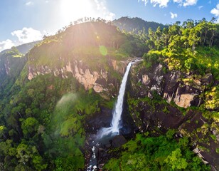 Waterfall cascades down a lush, green cliff face, sunlight shining through trees, and blue sky