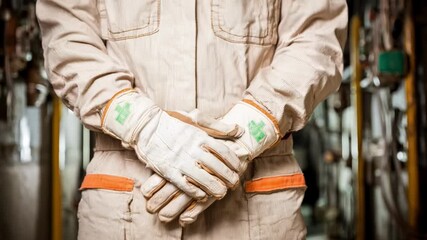 Close medium shot of a technician wearing durable gloves designed for safe beryllium handling in an industrial environment with visible safety protocols.