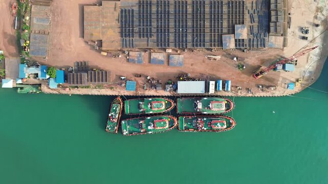 Aerial panorama of a bustling industrial shipyard, showcasing docked workboats and extensive steel