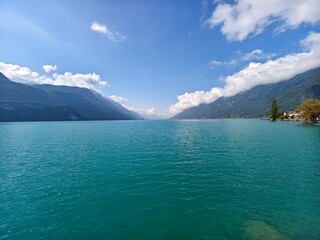 Wide-angle vista of turquoise water of Lake Brienz and the surrounding Alpine mountains in...