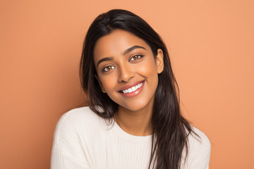 Beautiful Indian South Asian Woman Young Happy Smile Portrait Cream Sweater Peach Background Studio Headshot Radiant Joyful Fresh Graduate Professional Authentic Copy Space
