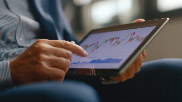 Man analyzing stock market data on a tablet. - Powered by Adobe