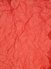A close-up view of vibrant red tissue paper featuring a heavily crumpled and textured surface.