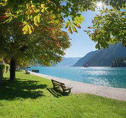 idyllic lake shore Achensee with benches under chestnut trees. tourist destination tyrol, austria