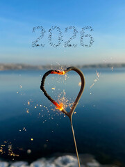 sparkler heart on the beach with flying birds in shape of 2026