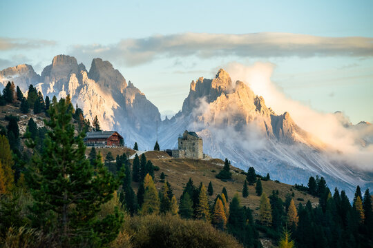 Castle on a Hill with a Mountain and Forest surrounding. Prato Piazza Fort in Dolomites Italy in autumn fall - clouds at sunset - mountainous