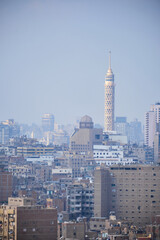 Vertical cityscape view of Cairo featuring dense urban architecture and prominent landmark TV tower rising above residential and commercial buildings