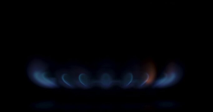 Gas stove burner ignition to shutdown, blue flame on black background, static side close-up, loopable