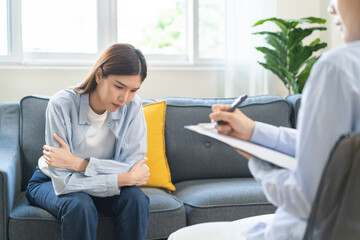 Obraz premium Psychology, depression. Suffer asian young woman consultation with psychologist while patient counseling mental therapy, doctor hand taking notes at clinic. Psychologist with sick mental health person