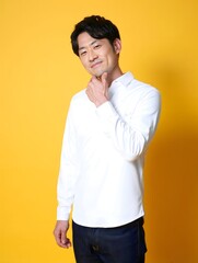 Smiling Man in White Shirt and Dark Jeans Against Yellow Background