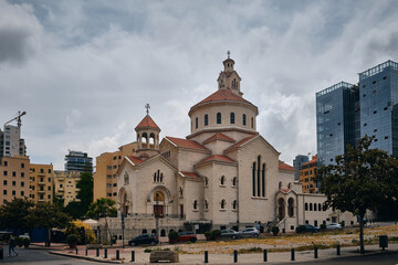 Christian church with domes and bell tower located in urban square, surrounded by modern high-rise buildings. Saint Elias and Saint Gregory the Illuminator Armenian Catholic Cathedral, Beirut, Lebanon