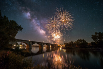Fireworks illuminating a starry night sky over a bridge