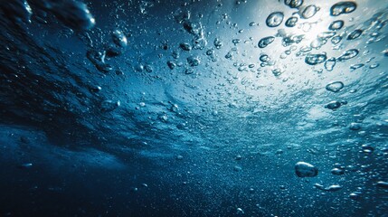 Underwater view of bubbles rising in ocean water with sunlight background for nature designs