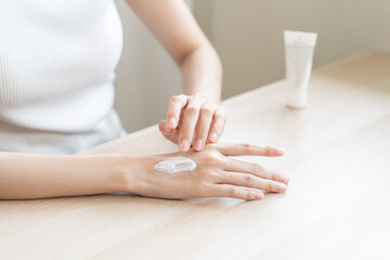 Healthy skin care, beauty asian young woman hand applying moisturizer, putting cream treatment on back hand after shower bath at home, makeup routine in the morning, treatment skin care body concept.