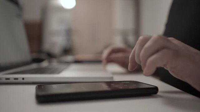 Multitasking Man Browsing Smartphone While Working on Laptop